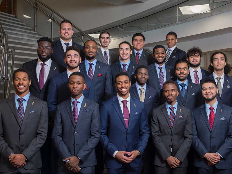 18 Young men pose for a photo in suits and ties.